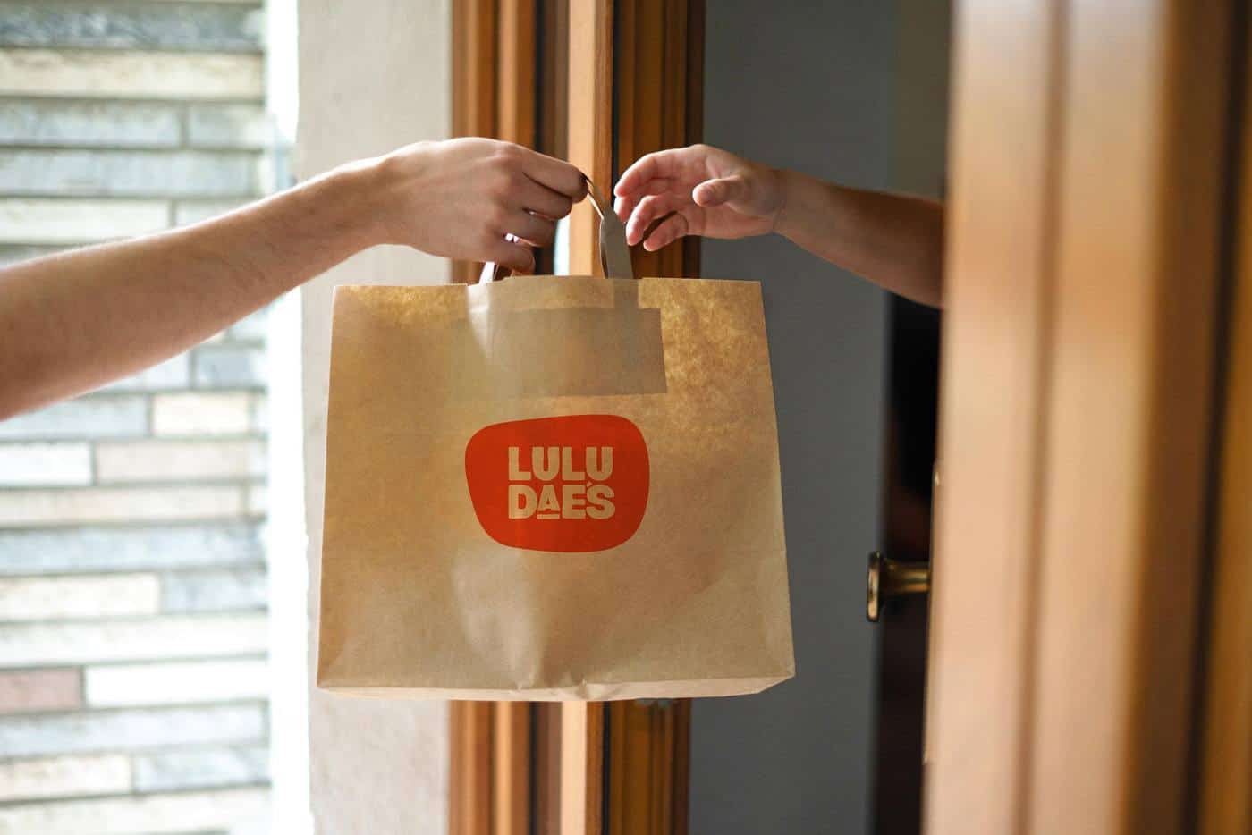 A Lulu Dae's takeaway bag handed across a doorway