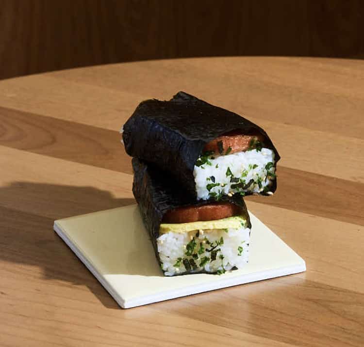 Two Spam musubi stacked on a tile, one with baked scallion egg