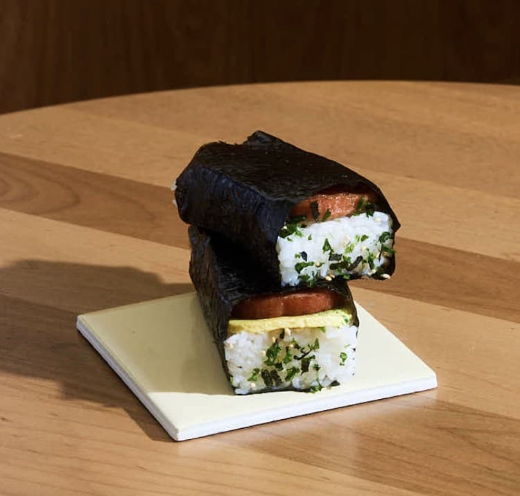 Two Spam musubi stacked on a tile, one with baked scallion egg