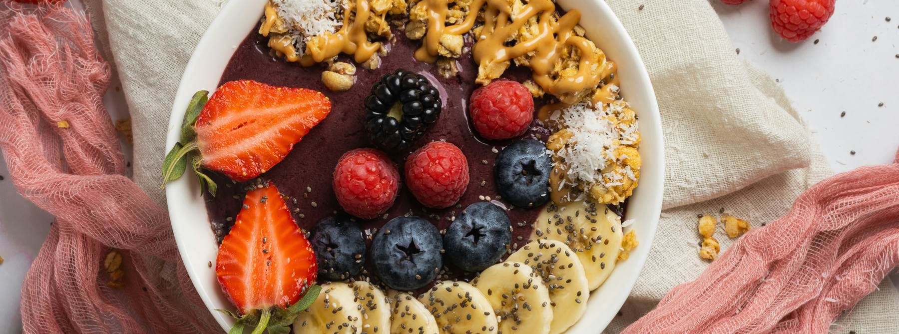 Açaí bowl with berries, banana and granola on linen
